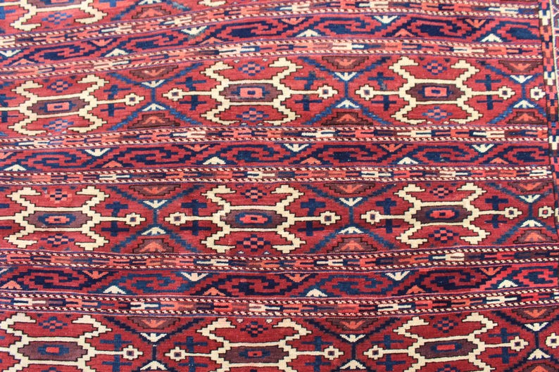 May include: A close-up of a red, blue, and white patterned rug with a geometric design. The rug has a traditional Persian style.