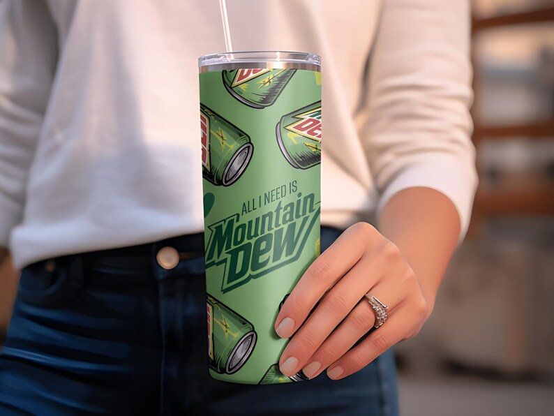 Puede incluir: Un vaso verde con un patr&oacute;n repetido de latas de Mountain Dew y el texto "ALL I NEED IS Mountain Dew". El vaso tiene una pajita blanca y una tapa plateada. El dise&ntilde;o est&aacute; sobre un fondo verde claro.