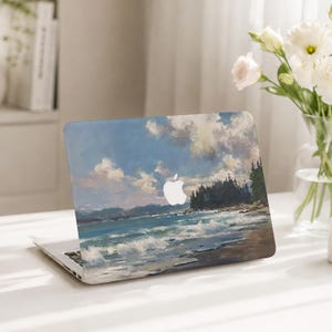 May include: A laptop featuring a protective skin with an oil painting style landscape of a coastal scene. The artwork depicts blue ocean waves crashing onto a sandy shore, a dark green forest line, and a cloudy sky with a white Apple logo in the center.