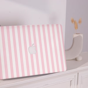 May include: A laptop featuring a pink and white striped pattern. The laptop displays a silver Apple logo. The device is positioned on a white surface.