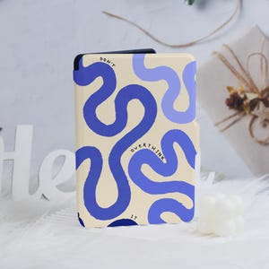 May include: A beige phone case with a blue abstract design of wavy lines and the words "DON'T OVERTHINK IT" in blue. The case is rectangular and has a black border.