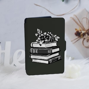 Op de afbeelding: Een zwarte e-reader hoes met een wit ontwerp van een stapel boeken met bloemen erop.