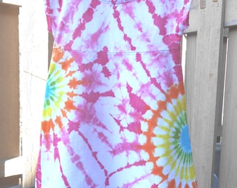 May include: A white tie-dye dress with pink, orange, yellow, and blue swirls. The dress has thin straps that tie at the shoulders.