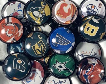 May include: A collection of 14 round hockey team logo keychains. The keychains feature logos from teams such as the Capitals, Oilers, Penguins, and more. The keychains are black with a clear plastic cover over the logo.