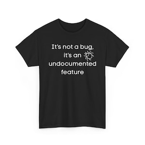 Può includere: T-shirt nera con testo bianco: "It's not a bug, it's an undocumented feature." Una grafica bianca di un insetto è accanto a "an". Design umoristico per sviluppatori.