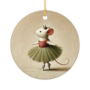 Op de afbeelding: Ronde keramische ornament met een ballerina-muis. De muis draagt een rode en groene tutu, een gouden kroon en balletschoenen. Het ornament heeft een gouden touwtje om op te hangen en een neutrale achtergrond.