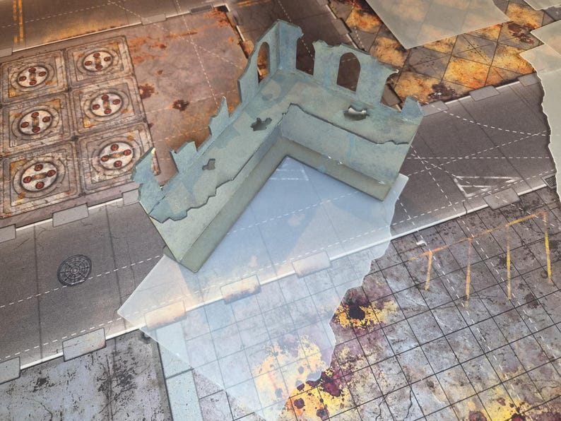 May include: An L-shaped miniature wargaming terrain piece featuring a ruined concrete wall structure with arched window cutouts and jagged, weathered edges. The model is painted in muted grey tones with subtle blue undertones and distressed textures.