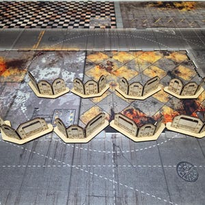 May include: Eight modular laser-cut wooden barricades arranged in two rows. Each barricade features a curved, segmented design with rectangular cutouts and etched industrial detailing, providing a defensive structure for tabletop gaming.