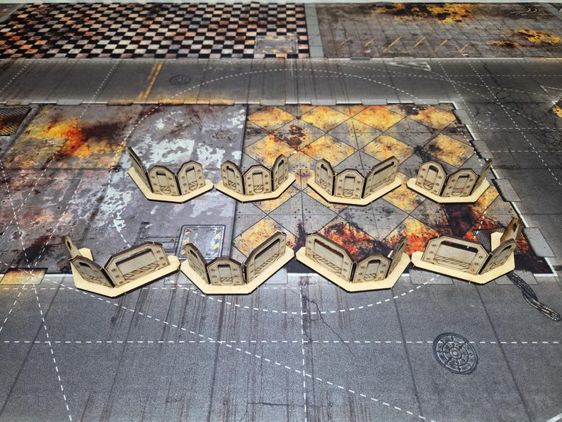 May include: Eight modular laser-cut wooden barricades arranged in two rows. Each barricade features a curved, segmented design with rectangular cutouts and etched industrial detailing, providing a defensive structure for tabletop gaming.