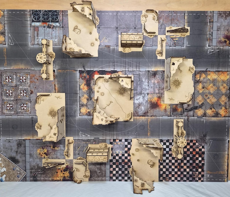 May include: A tabletop gaming terrain set featuring laser-cut light wood structures with jagged, ruined edges arranged on a printed mat. The mat displays a dark, weathered urban street layout with sections of gray pavement, checkered patterns, and debris.