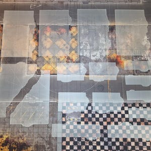 May include: A collection of translucent, rectangular acrylic templates arranged over a printed game mat featuring industrial, weathered textures, yellow hazard stripes, and a black and white checkered pattern across the surface.
