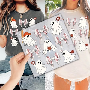 May include: Two t-shirts, one gray and one cream, feature a baseball-themed design. The design includes cartoon ghosts with baseball bats, gloves, and baseballs, along with baseball bow accents. The design is printed on the front of the shirts.