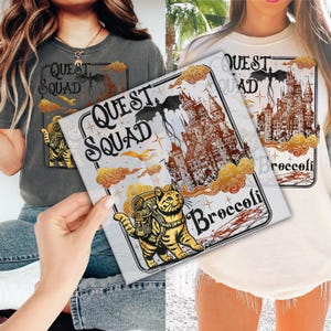 May include: Two women wearing t-shirts with a graphic design featuring a cat, a dragon, a castle, and the text "Quest Squad" and "Broccoli".