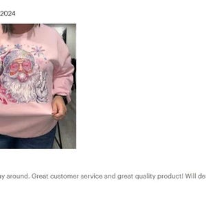 a woman wearing a pink sweatshirt with a santa clause on it