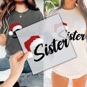 May include: Two t-shirts, one dark grey and one cream, each with a Santa hat graphic and the word "Sister" in black script. The Santa hats are red with white trim and a white pom-pom.