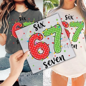 May include: Two t-shirts, one gray and one white, each featuring the number "67" in a festive design. The number "6" is red with white polka dots and the number "7" is green with white polka dots. The word "six" and "seven" are also displayed.