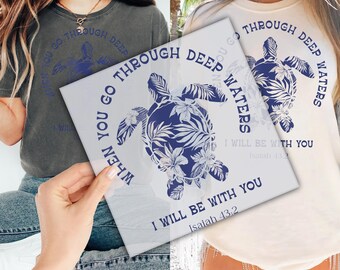 May include: Two t-shirts, one gray and one cream, each featuring a blue turtle design with floral accents. The text reads "WHEN YOU GO THROUGH DEEP WATERS, I WILL BE WITH YOU, Isaiah 43:2."