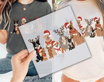 May include: A white and gray t-shirt with a design of dogs wearing Santa hats and reindeer antlers. The dogs are all different breeds and sizes. The design is in a cartoon style and is very festive.