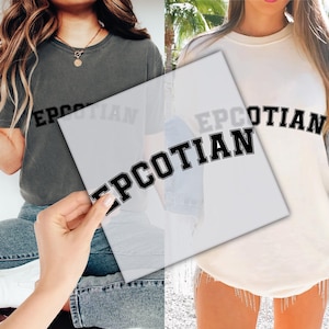 May include: Two t-shirts, one charcoal gray and one cream, each with the word "EPCOTIAN" printed in black block letters. The gray shirt is short-sleeved, and the cream shirt is long-sleeved.