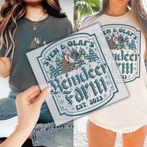 May include: Two t-shirts, one gray and one cream, featuring a graphic with the text "Sven & Olaf's Reindeer Farm EST. 2013". The graphic includes a reindeer and pine trees in a teal and brown color scheme.