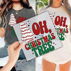May include: Two t-shirts, one dark gray and one cream, each featuring a Christmas tree design and the words "OH, CHRISTMAS TREE" in red and green. The design includes a star pattern.