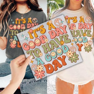May include: Two t-shirts with a retro 70s design featuring the text "It's a good day to have a good day" with peace signs and smiley faces.