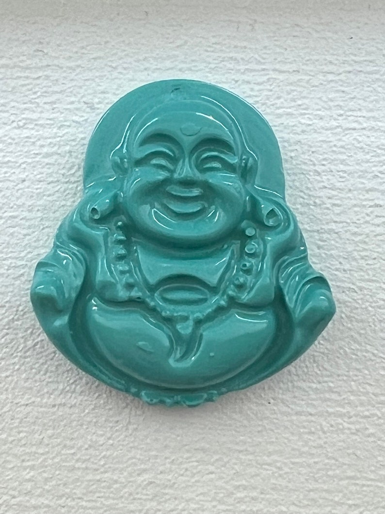 May include: A teal green jade carving of a smiling Buddha figurine.