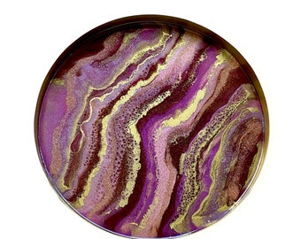 May include: Round tray with a gold rim and a purple, pink, and gold resin design. The resin has a marbled, swirled effect.