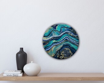 May include: Round abstract painting with blue, green, and gold swirling patterns. The painting has a textured, glittery finish.