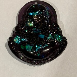 May include: A black and iridescent glass figurine of a smiling Buddha. The figurine has a round, plump body and a serene expression.