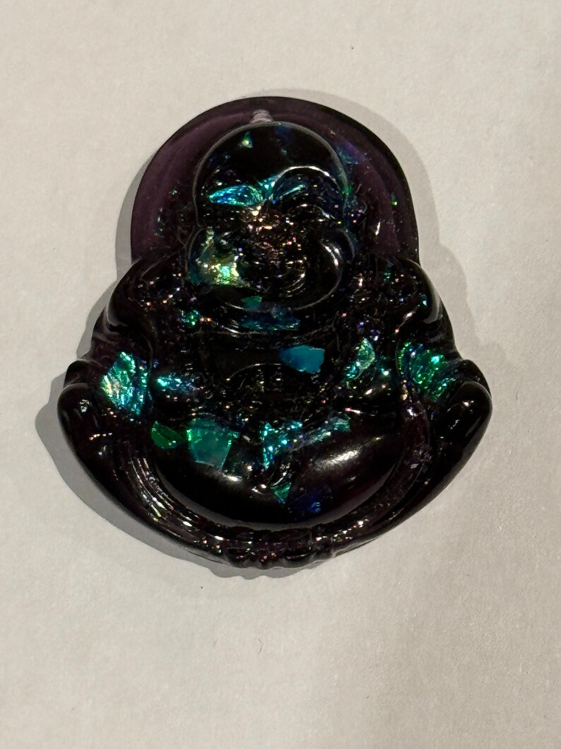 May include: A black and iridescent glass figurine of a smiling Buddha. The figurine has a round, plump body and a serene expression.