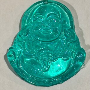 May include: A teal blue resin figurine of a smiling Buddha with glitter embedded in the resin.