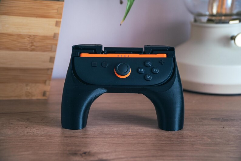 K&ouml;nnte beinhalten: Eine wei&szlig;e Keramik-Tasse mit schwarzem Henkel und dem Text "But First, Coffee" in schwarzer, handschriftlicher Schrift. Die Tasse steht auf einer wei&szlig;en Oberfl&auml;che.