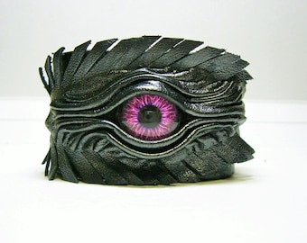 Bracelet en cuir fait main.  Manchette réglable en cuir noir avec plumes, oeil de dragon.
