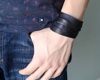 Könnte beinhalten: Ein schwarzes Lederarmband mit doppelter Wicklung. Das Armband wird am Handgelenk getragen.