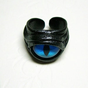 Peut inclure: Une bague en cuir noir avec un motif &oelig;il de chat bleu.
