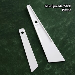 May include: Two white plastic glue spreader sticks. The larger stick is 40mm wide and the smaller stick is 20mm wide.