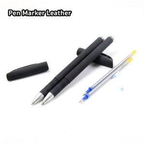 Pode incluir: Duas canetas pretas com pontas prateadas e uma tampa preta. As canetas estão sobre uma superfície branca. Também há três recargas de tinta azuis e amarelas na superfície. O texto "Pen Marker Leather" é visível no canto superior esquerdo da imagem.
