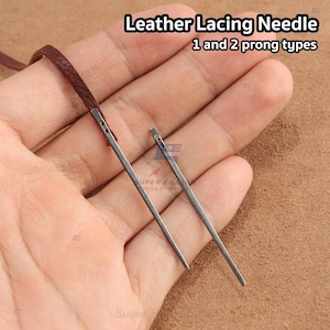 May include: Two metal leather lacing needles with brown leather cord. The needles are silver and have either one or two prongs. The text "Leather Lacing Needle 1 and 2 prong types" is at the top of the image.