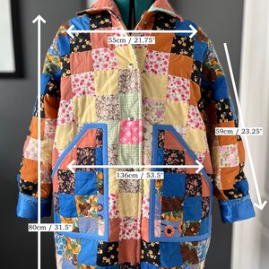 A colourful quilted jacket is displayed on a teal mannequin.  It features a patchwork design with various floral & patterned squares in shades of blue, pink, yellow, orange, and green.  Blue trim outlines the pockets and edges.