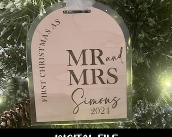 Op de afbeelding: Een lichtroze houten kerstversiering met de tekst "First Christmas as Mr. and Mrs. Simons 2024" in bruine letters.