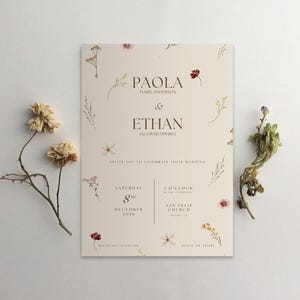 Pu&ograve; includere: Un invito di nozze con sfondo crema e dettagli floreali. L'invito recita "Paola Marie Anderson & Ethan Jacob Humphrey" e include la data "Sabato 8 dicembre 2026" e l'ora "2 del pomeriggio". L'invito include anche la location "San Feliz Church, Malibu, CA" e il dress code "Black Tie Attire".