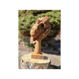 Antique cast iron sculpture of a pensive man&#39;s face. Rustic figurine garden and home decoration. Beautiful and stylish cast iron sculpture