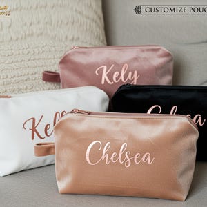 May include: A collection of personalized velvet pouches in various colors: white, blush pink, peach, and black. Each pouch features a rose gold zipper and a matching handle. The names "Kely", "Chelsea", and "Colea" are printed on the pouches.