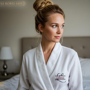 May include: White waffle robe with the name "Lewis" embroidered on the chest. The robe has a shawl collar and a textured, grid-like pattern. The image also shows the text "WAFFLE ROBES EMB" at the top and "Party Princess" at the bottom.