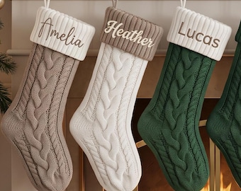 Puede incluir: Seis calcetines navideños de punto trenzado colgados de una repisa, cada uno con un puño doblado bordado con los nombres Amelia, Heather, Lucas, Daniel, Carol y Andrew. Los calcetines son de color beige, blanco, verde, verde oscuro, rojo y burdeos.