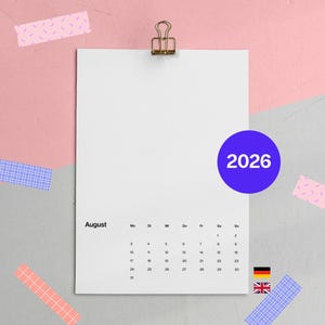 Könnte beinhalten: Ein weißes Kalenderblatt für August 2026, gehalten von einer goldenen Klammer, mit einem blauen Kreis, der das Jahr anzeigt. Der Hintergrund ist eine Mischung aus Rosa und Grau, verziert mit gemustertem Klebeband.