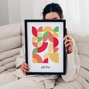 May include: A framed print with a geometric design in shades of red, yellow, green, and orange. The print has the word "pêche" written at the bottom.