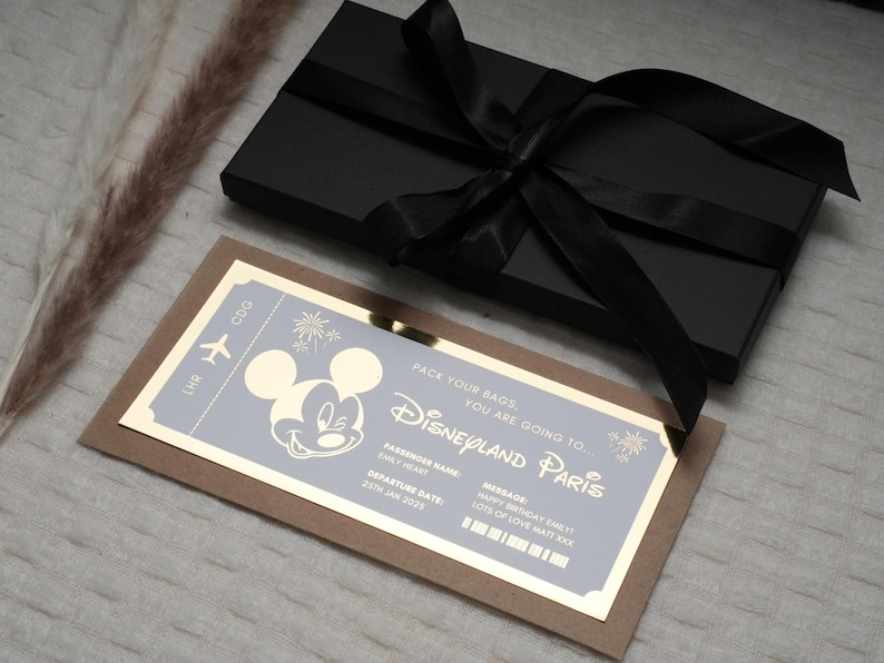 May include: A gold-colored ticket with a Mickey Mouse illustration and the text "Pack your bags, you are going to Disneyland Paris". The ticket is on a brown background.