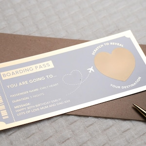 Op de afbeelding: Een gouden en blauwe instapkaart met een kraslot-hart om een bestemming te onthullen. De tekst luidt "Boarding Pass You Are Going To... Passenger Name: Emily Heart Duration: 5 Nights Message: Happy 30th Birthday Emily Lots of Love Mum and Dad XXX Scratch to Reveal Your Destination"
